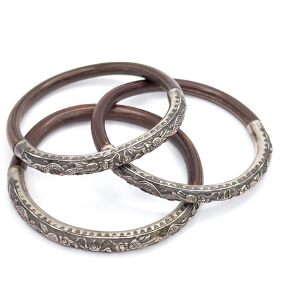 Three bangles laid out loosely in a fanned triangle rather than a neat stack, each full circle visible so the silver sections and their joins with the brown wood can be followed right around.