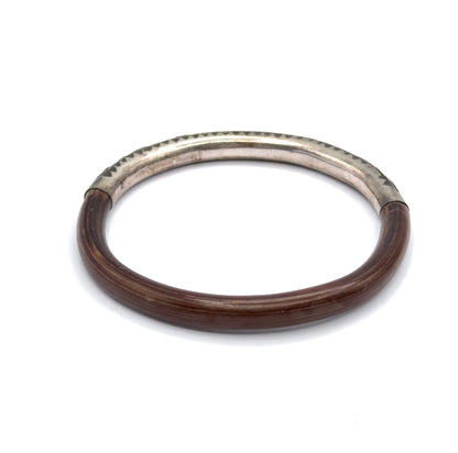 Looking down into the open circle of the bangle, with the silver section set at the far side so both joins where metal meets wood are visible against the rounded band.