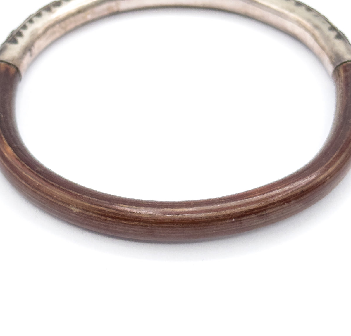 Close view of the lower half of the bangle, where the smooth deep brown wood shows fine lengthwise grain lines before rising to meet the silver section at both joins near the top.