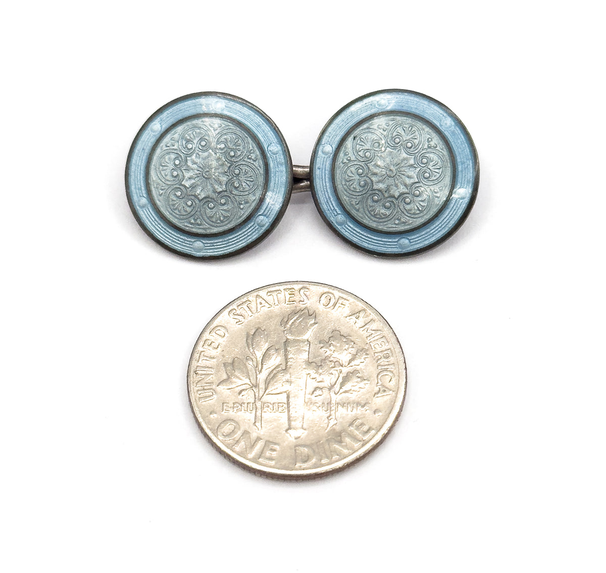 Both enamel discs face up beside a dime for scale, the engine-turned rosette and scrollwork pattern showing through the grayish and dusty blue enamel within the sterling silver rims.