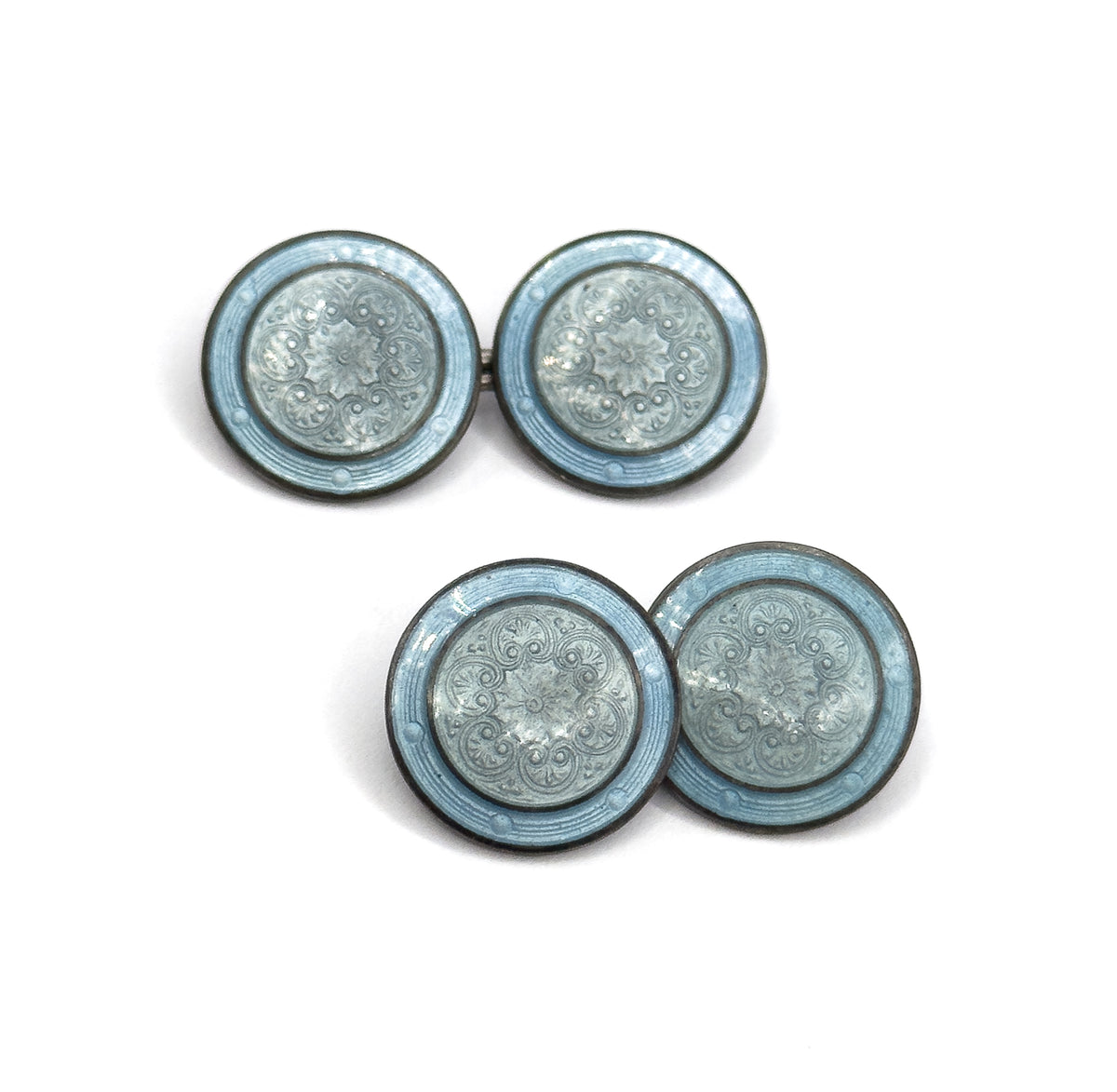 Both cufflinks lie flat and face up in a stepped diagonal, all four enamel discs seen straight on so the rosette centres and dusty blue outer bands read as matching pairs.