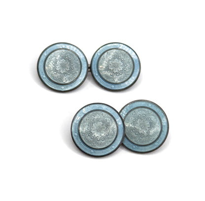 Both cufflinks lie flat and face up in a stepped diagonal, all four enamel discs seen straight on so the rosette centres and dusty blue outer bands read as matching pairs.