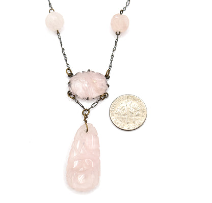 A dime laid beside the lower half for scale, the pronged oval centre station reading about the width of the coin and the long carved rose quartz drop roughly twice its length.