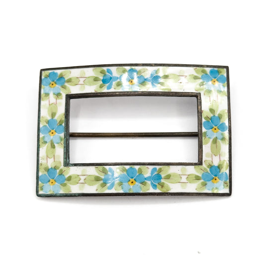 Straight-on front view with no scale object, the rectangular enamel band of blue and yellow flowers filling the frame and the pin stem crossing the open centre as a slim bar.