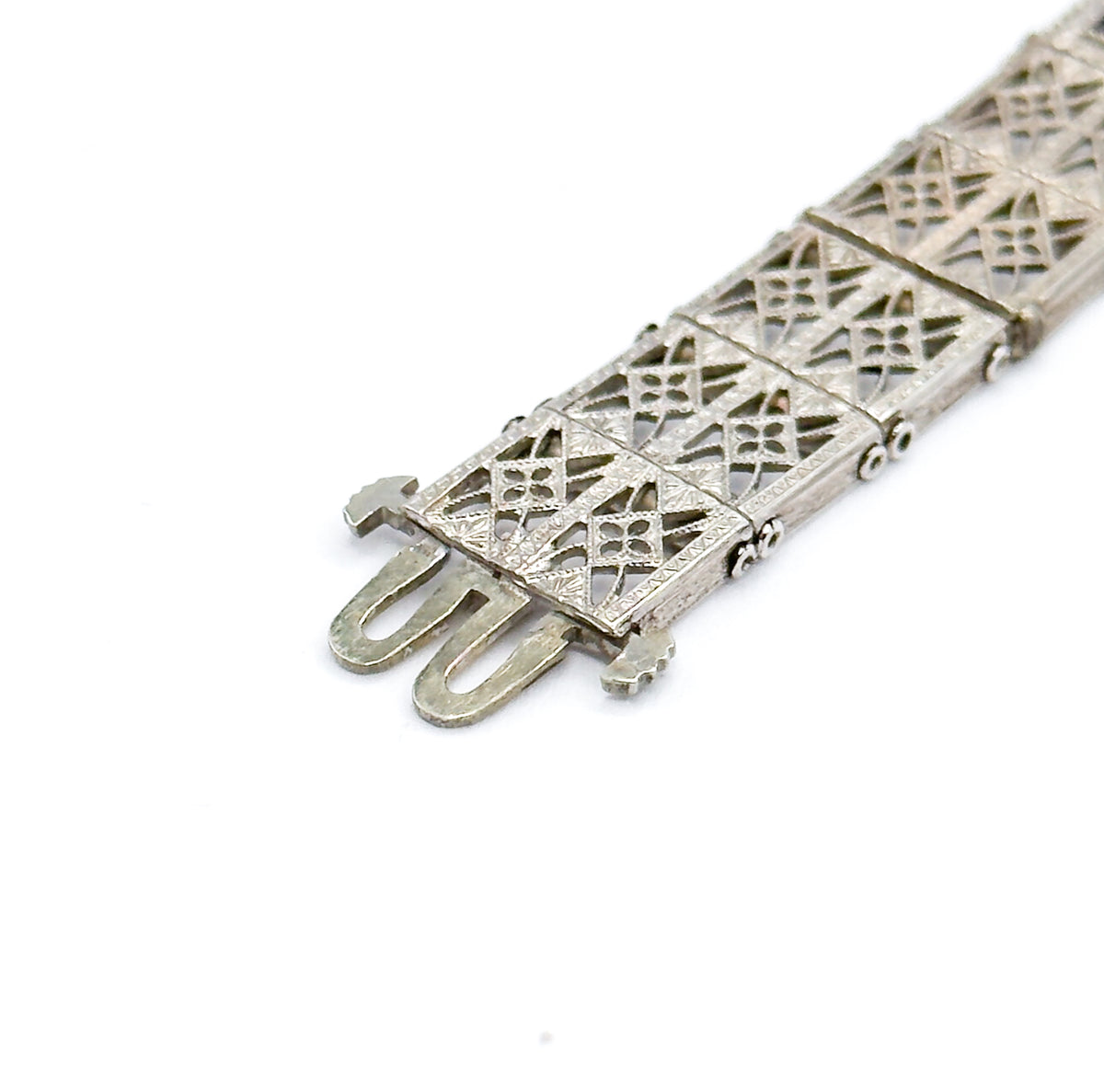 A close-up of the clasp end, where two slim U-shaped tongues extend from the final sterling silver filigree link patterned with lattice openwork.