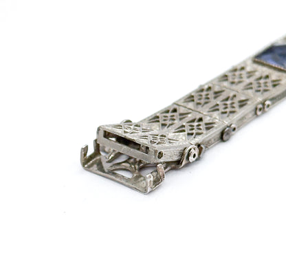 Almost the same view with slightly different angle, tipped to show the open rectangular clasp box beneath the lattice links, with the two tongues and the round hinge pins along the side.