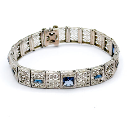 The whole bracelet standing in an open oval, seen from above, so the full circuit of filigree links reads at once with blue paste squares and rectangles spaced around the front.