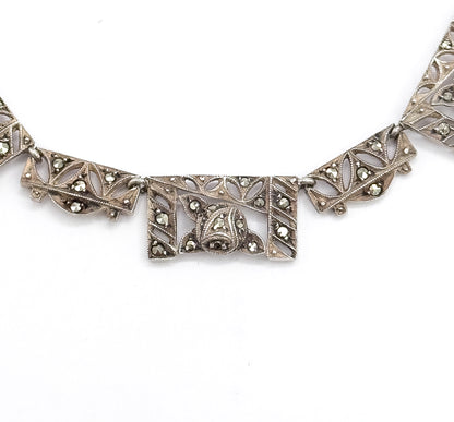 Tight crop on the central rectangular panel, its domed marcasite-set motif and pierced leaf openwork sharply visible between two chevron panels, with milgrain edging along every border.