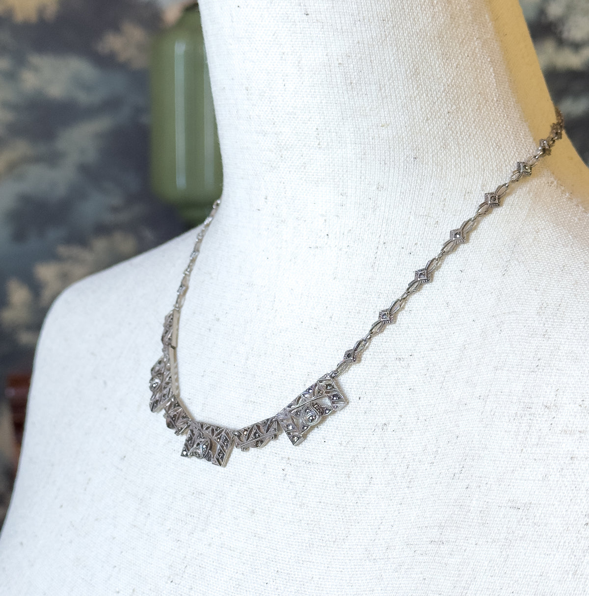 Art Deco sterling silver marcasite link necklace shown at the neck on a cream linen bust form, its graduated angular front links leading into a slim chain of small shaped links.