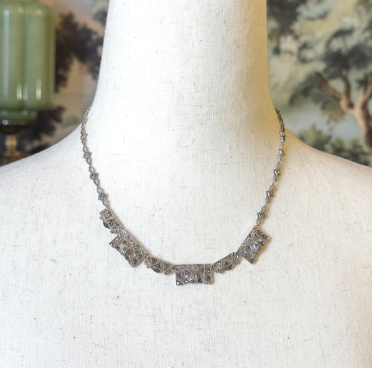 Closer frontal view showing the five graduated rectangular front panels set with small grey marcasites in milgrain-edged metalwork, the slim chain rising evenly on both sides toward the nape.