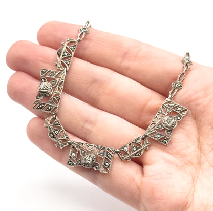 Shown draped across an open palm, which gives a sense of scale: each rectangular panel spans roughly a fingertip, linked by small shaped chain sections.