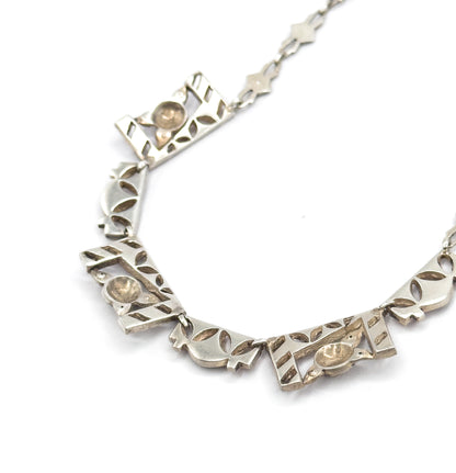 Reverse view along the curve of the necklace, showing several panels' pierced undersides with their smooth oval plaques and the open star-shaped chain links trailing away.