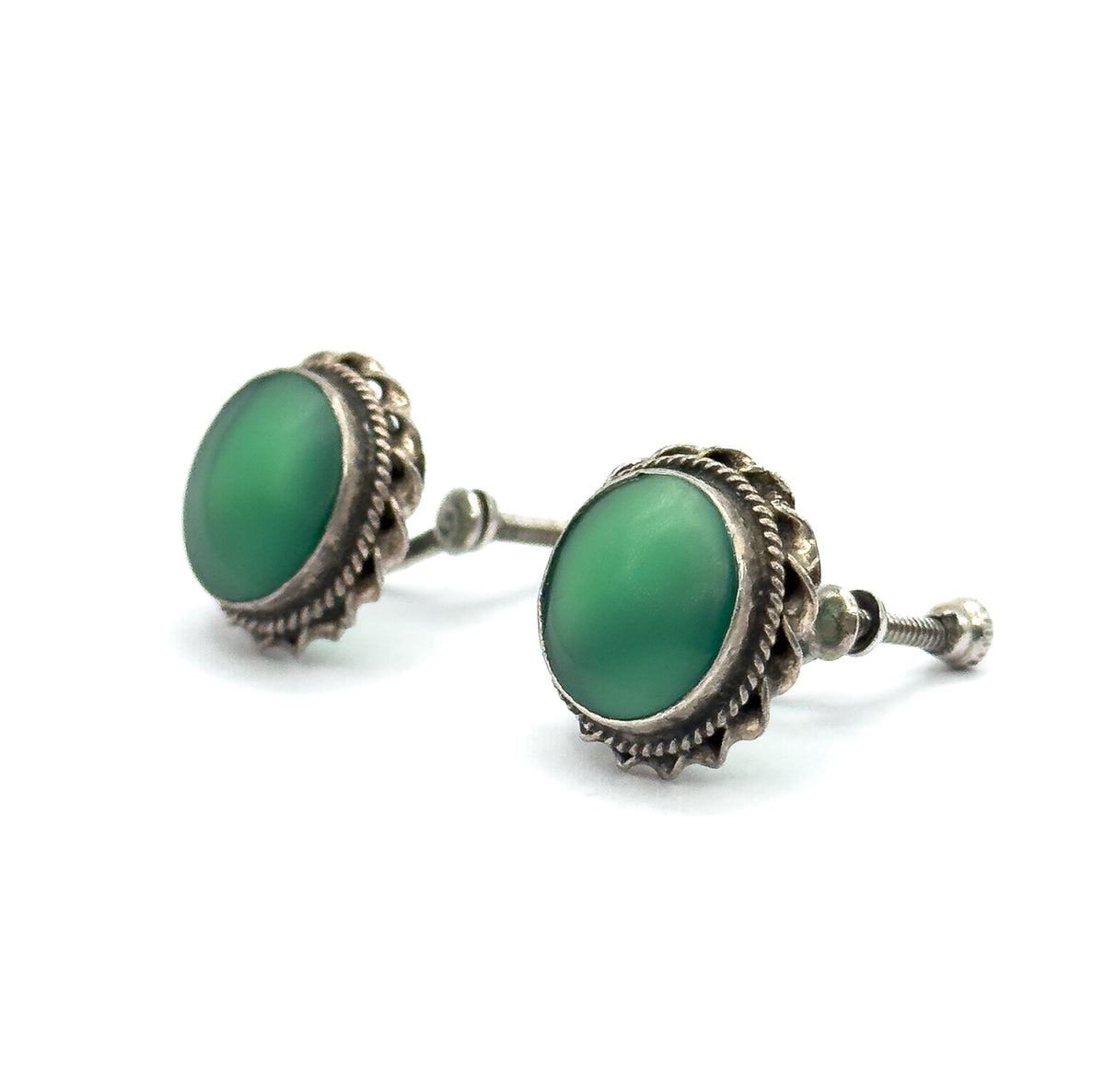 A low side view showing the green cabochons in profile within their bezels, with one screw-back threaded post extending clearly to the right.