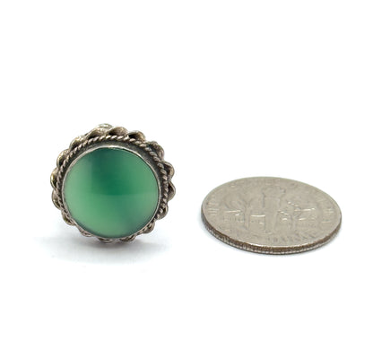 One earring alone beside a dime for scale, its round green chrysoprase cabochon and cable-textured sterling silver bezel barely larger than the coin.