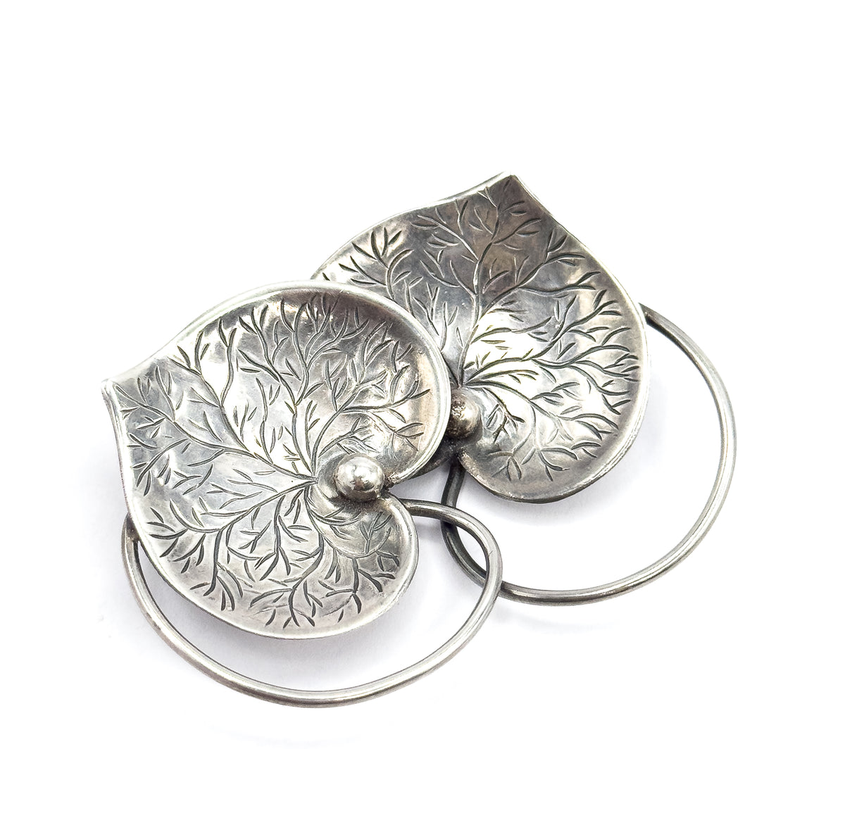 Overhead view on white showing the two etched hearts overlapping point-down, their central beads side by side, with the connector wire forming two open circles behind them.