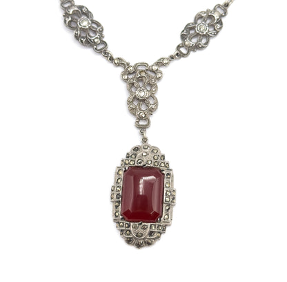 Straight-on symmetrical view of the necklace front, two floral openwork marcasite stations flanking the central drop-shaped link from which the carnelian pendant hangs squarely below.