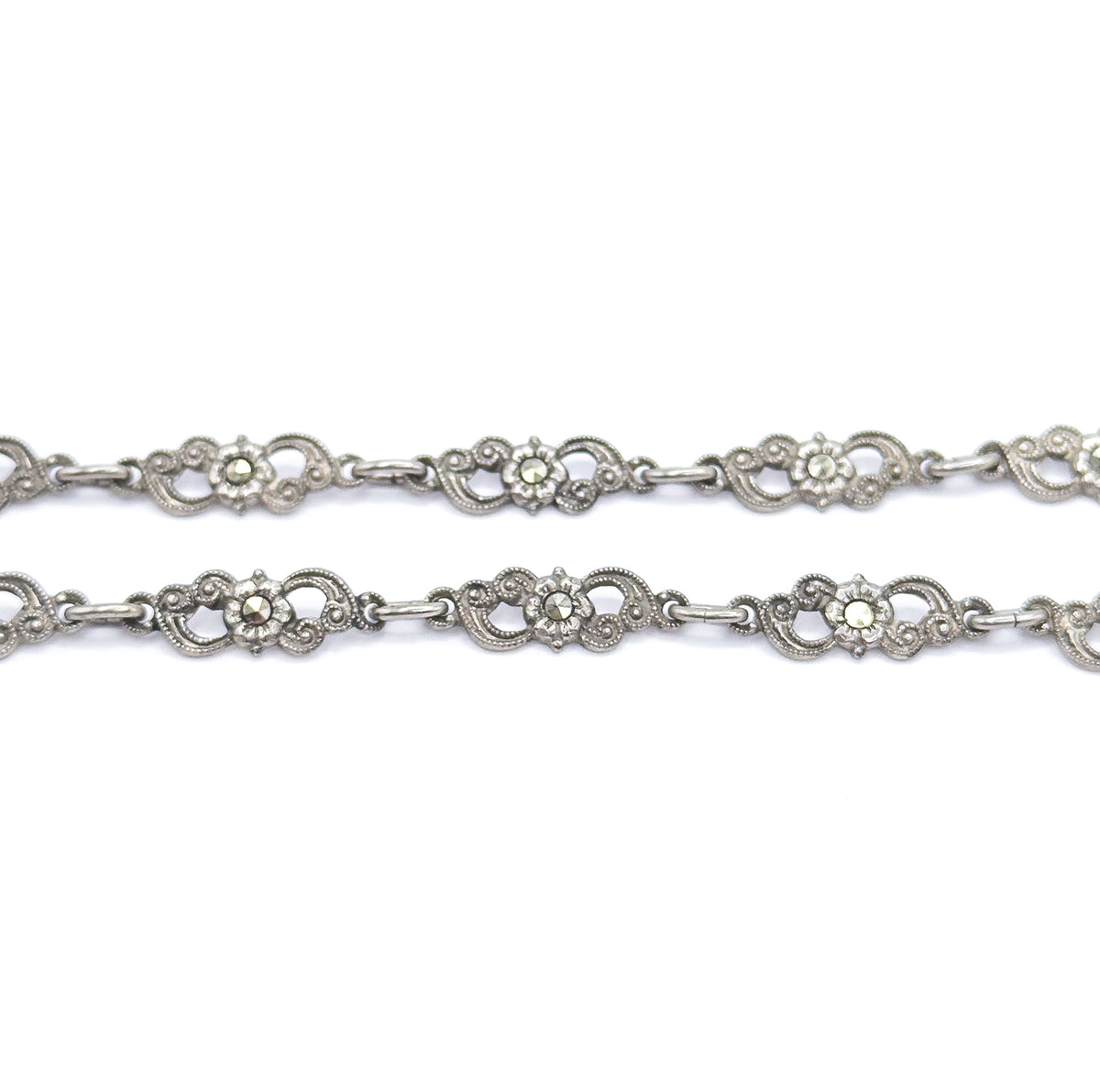 Two parallel runs of the chain fill the frame, each scrolled sterling silver station centred with a marcasite-set flower and joined by short oval connector links.