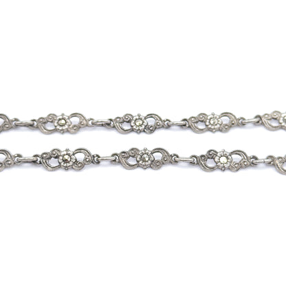 Two parallel runs of the chain fill the frame, each scrolled sterling silver station centred with a marcasite-set flower and joined by short oval connector links.