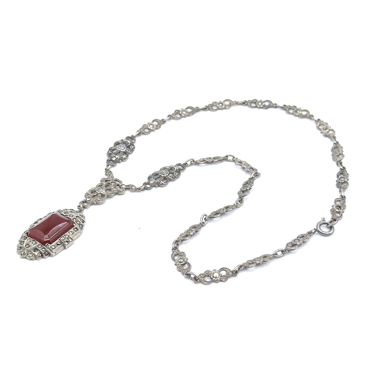 The whole necklace laid out flat in an open loop on white, carnelian pendant at the lower left and the marcasite-set chain stations curving round to the spring-ring clasp at the right.