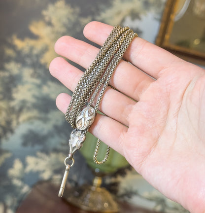 The chain draped over an open palm so the engraved sliding bead and the tapered scrolled fitting show clearly, with the swivel clasp hanging free below the fingers.