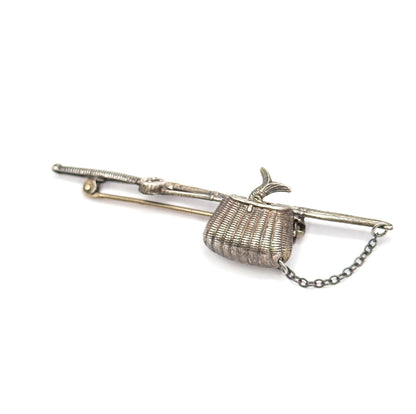 Raised three-quarter view from the pin side, the pole angled away to the rod tip at upper left, basket and fish tail at centre and the safety chain swinging in a loop below.