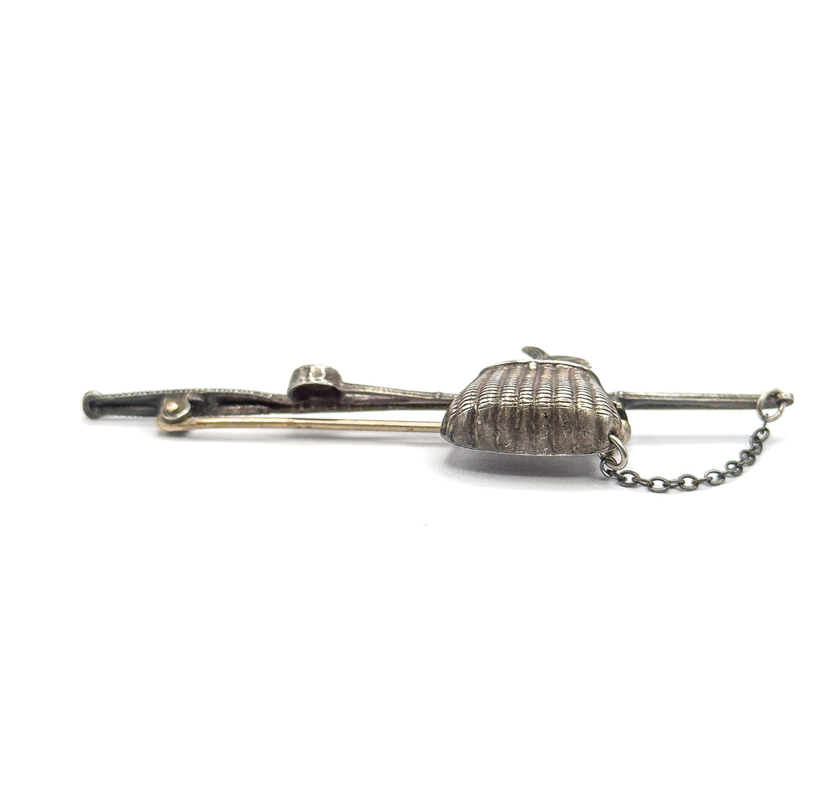 Low side view across the brooch with the ribbed basket turned towards the camera, the pin stem lying tight against the pole and the safety chain draped to the right.
