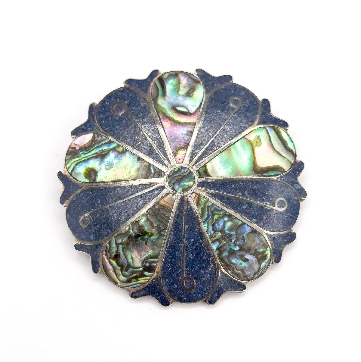 Straight-on overhead view of the whole round face, the full pinwheel of alternating iridescent shell and deep blue crushed stone wedges ringed by the scalloped silver rim.