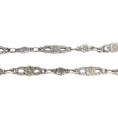 Two parallel runs of the sterling silver chain side by side, showing both faces of the pierced oval panels and round blossom links with patina deep in the recesses.