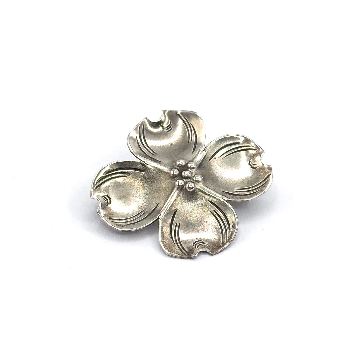 Front view with the flower turned slightly on the diagonal, so the cupped petal bowls catch the light unevenly and the bead cluster sits just off centre among the etched veins.