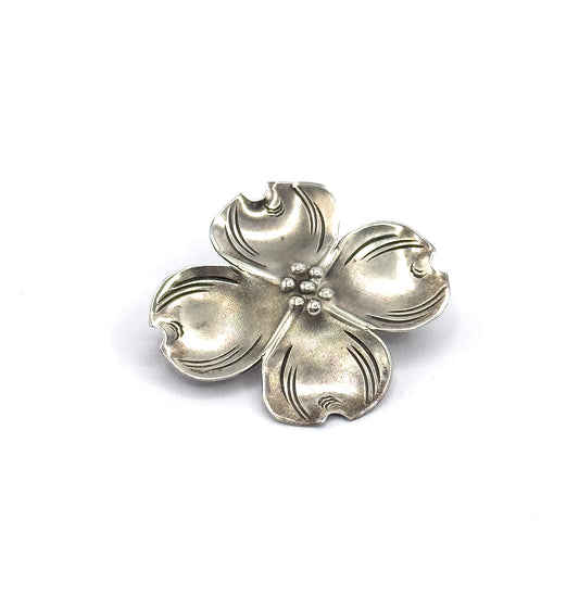 Front view with the flower turned slightly on the diagonal, so the cupped petal bowls catch the light unevenly and the bead cluster sits just off centre among the etched veins.