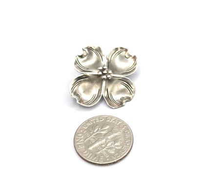 Vintage Stuart Nye sterling silver dogwood flower brooch, shown face-up on white beside a dime for scale, its four veined petals meeting at a cluster of small beads.