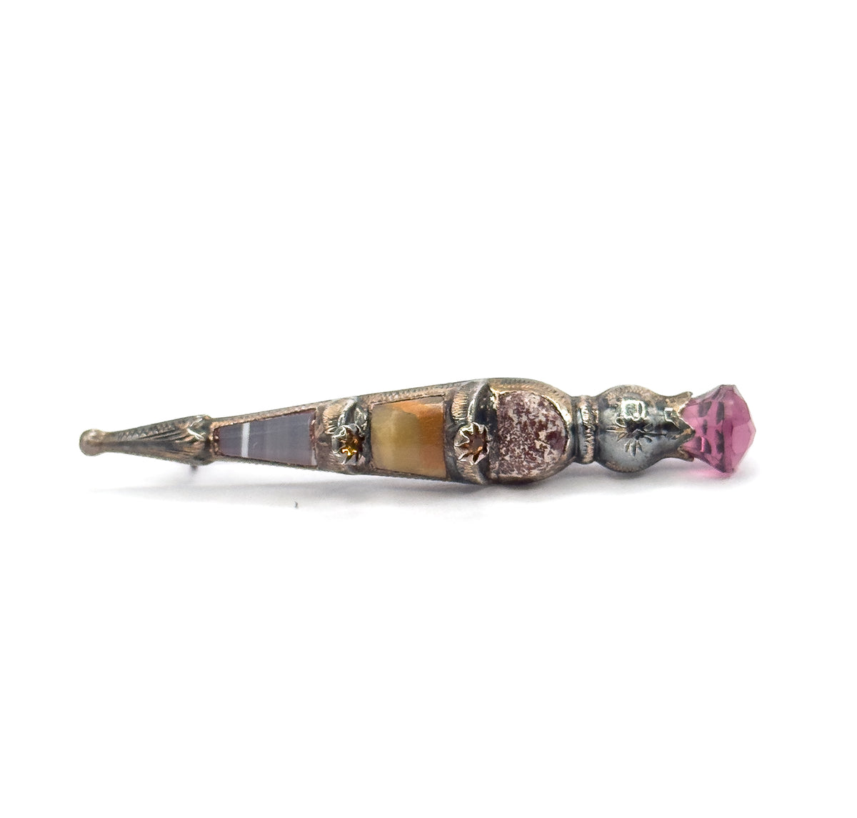 Low, nearly level side-on view with the pointed engraved tip at far left, the banded agate and onyx panels running in a line past two star-set golden paste accents to the faceted purple paste at right.