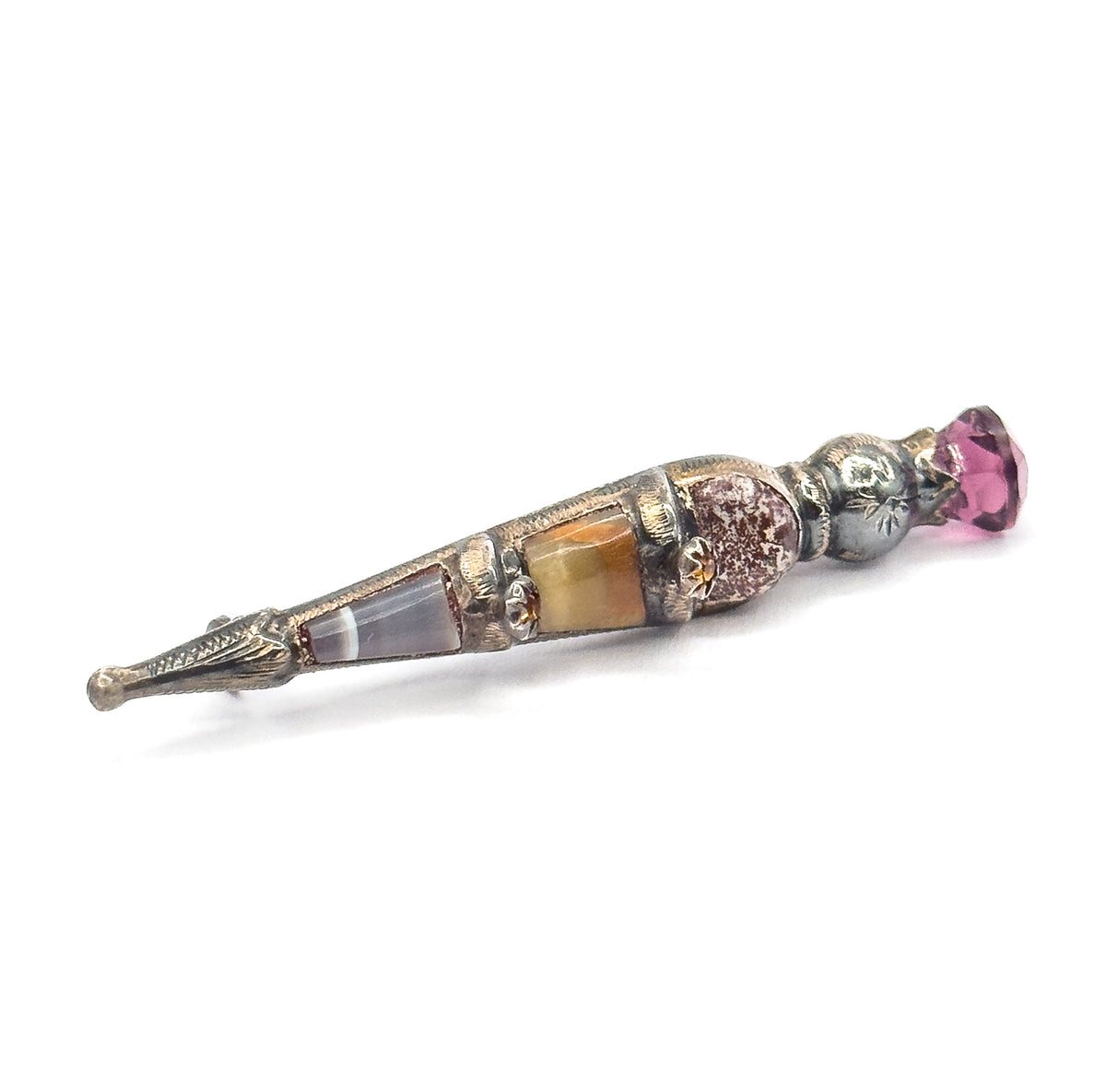 Three-quarter view from slightly above, the tapering engraved body angling up from the pointed tip at lower left through its agate and onyx panels to the faceted purple paste head.