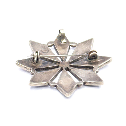 The reverse of the sterling silver starburst, showing the hinged pin stem across the open back, its catch and joint, the small bail at the top, and an AR stamp on one point.