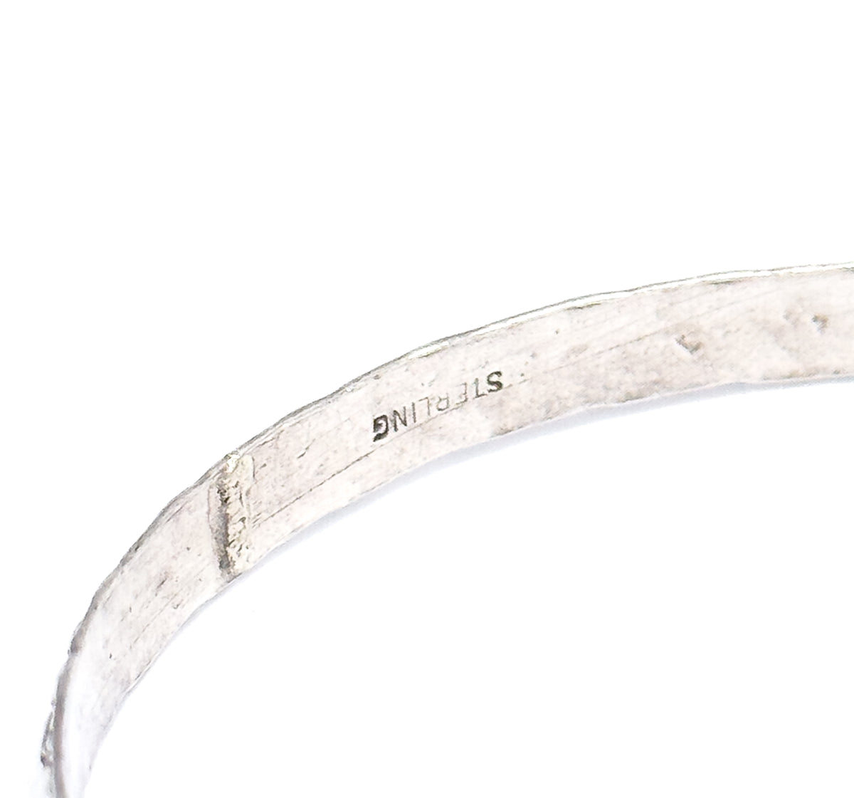 Almost the same view with slightly different angle, a tighter macro of the inner band turned upside down so the sterling stamp and the small rectangular mark beside it fill the frame.