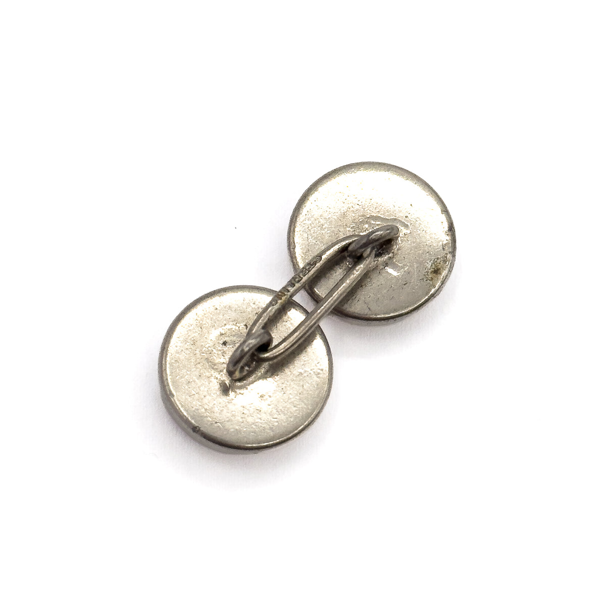 Closer view of one cufflink's reverse, the two domed silver backs angled towards the camera with tiny stamped lettering readable along the flat connecting link.