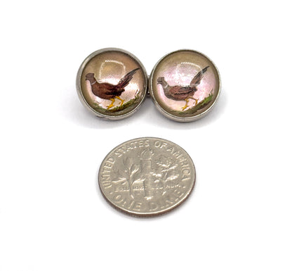 Two round painted faces side by side above a dime, showing the pheasants in their sterling bezels are each well under half the coin's width.