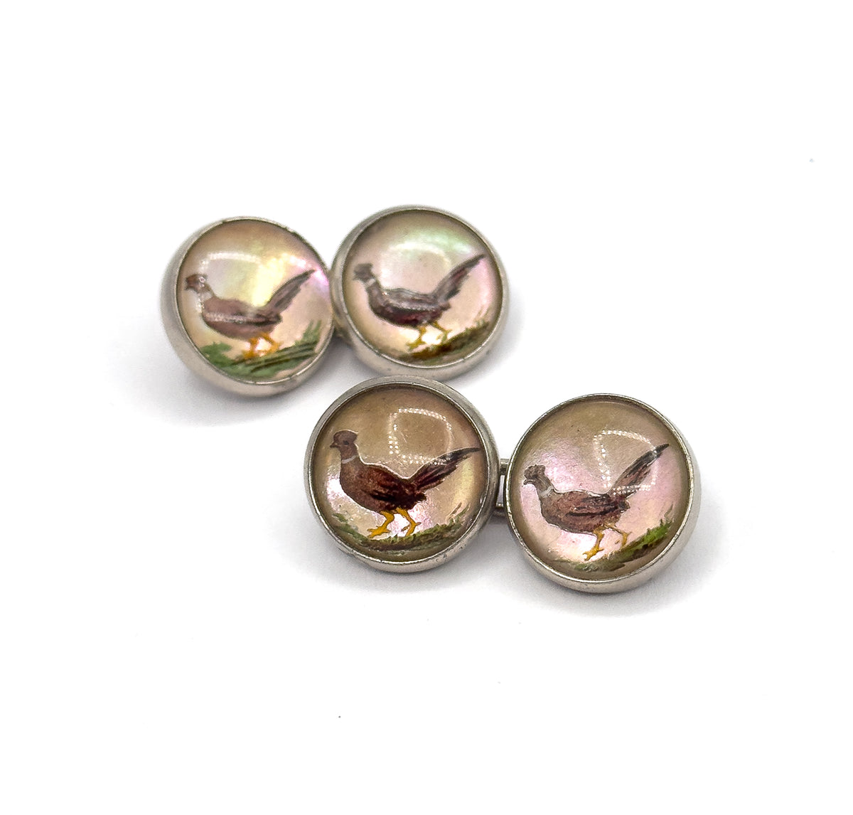Both cufflinks lie flat on white, one pair behind the other, seen from above so all four reverse painted pheasants show their pink and green iridescent grounds within smooth sterling bezels.
