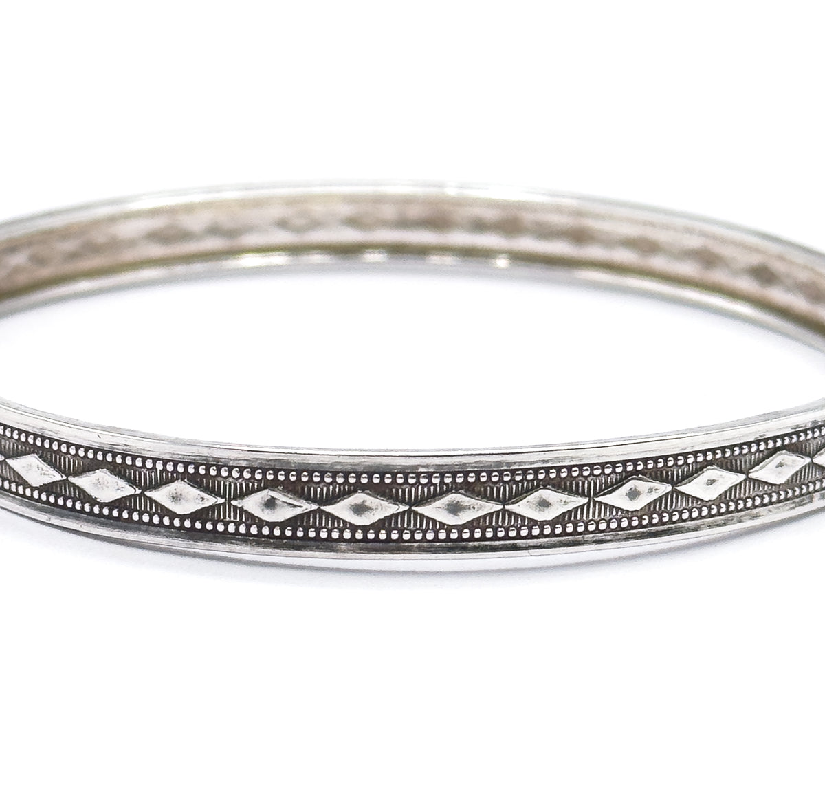 Tight crop on the front of the band, where rows of fine beading frame the diamond motifs and darker patina settles into the hatched background.