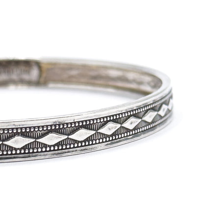 Steeply raking close-up where only a few diamond motifs stay in focus along the raised edge of the band, the plain inner wall blurring away into the background.
