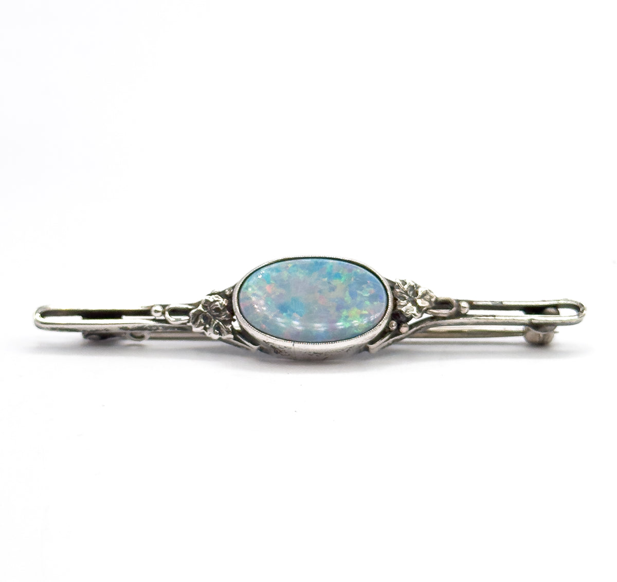 Straight-on front view with the bar level, the oval opal doublet flashing blue, green and pink in its bezel, floral silver mounts at each side and the pin stem just visible behind the bar.