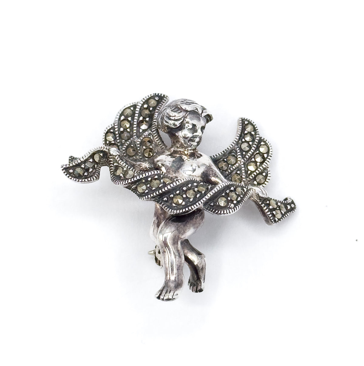 Vintage sterling silver marcasite cupid brooch, shown front-on against white, with round marcasite set along the milgrain-edged wings and draped cloth and the cherub's legs dangling below.
