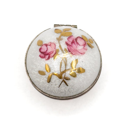 Round decorative item with pink roses and gold accents on a white background