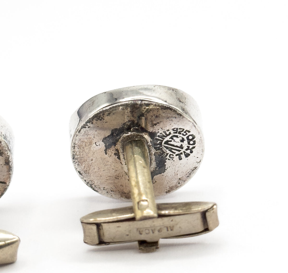 Macro view of the reverse, the stamped mark reading 925 clear on the rounded sterling silver back with its post and hinged toggle bar swung out below.