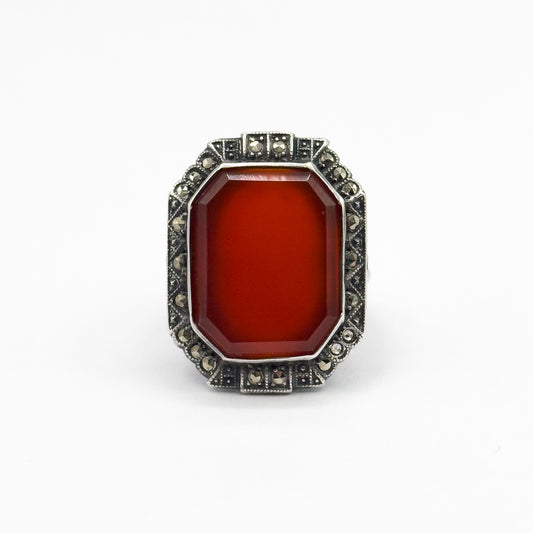 Art Deco carnelian and marcasite shield ring in sterling silver, shown face-up against a white background, the octagonal orange-red stone bezel-set within a stepped halo of small round marcasites.