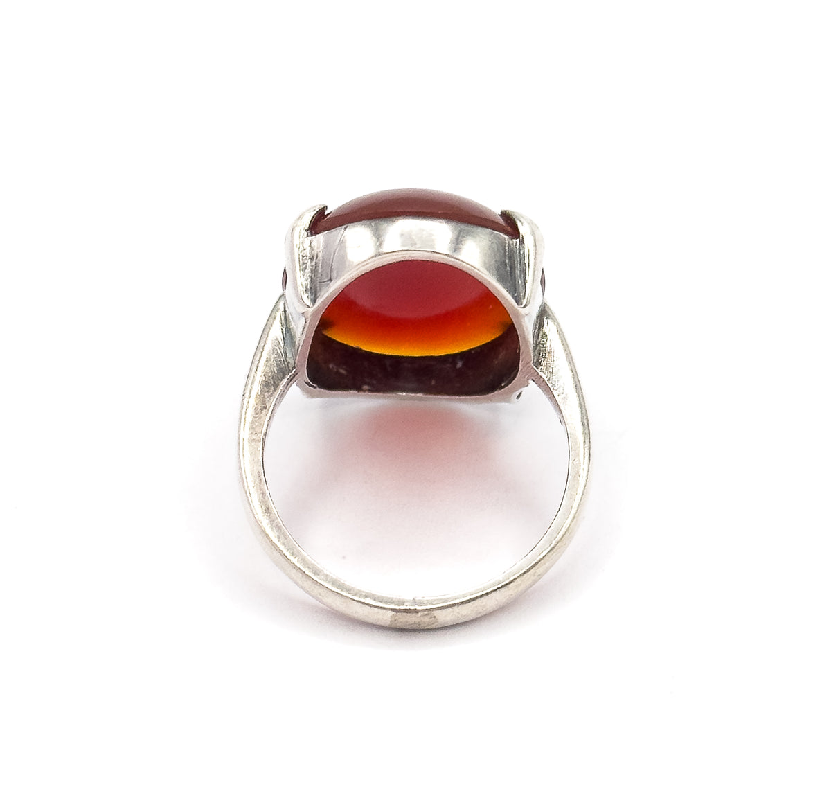 Looking into the open gallery from below, the underside of the red cabochon glows through the setting between the prongs, with the sterling silver shank forming a wide arch beneath.
