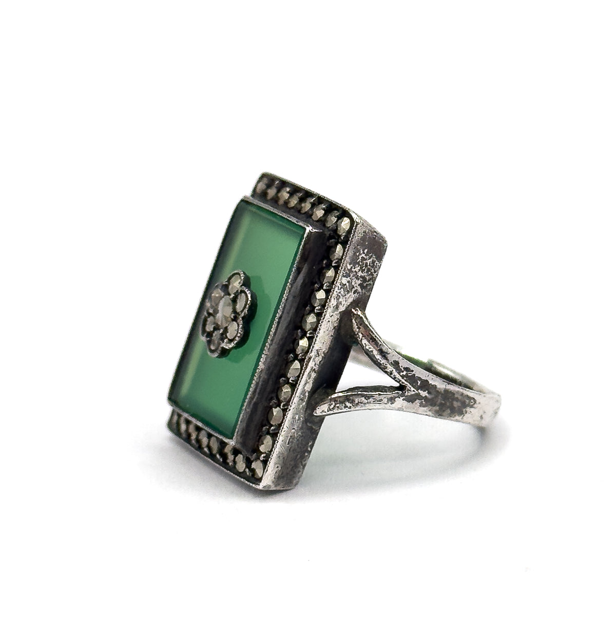 Angled three-quarter view where the whole rectangular chrysoprase face is visible, its central marcasite flower cluster and surrounding halo catching light above the patinated silver shank.