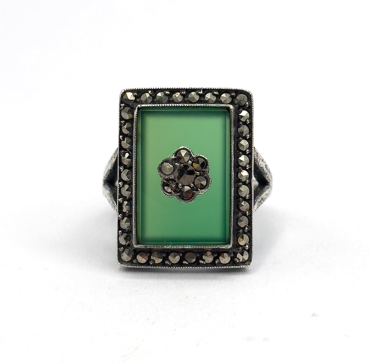 Straight down onto the flat rectangular face, the chrysoprase and its marcasite flower centred within the full square halo, the shank tucked out of sight behind the bezel.