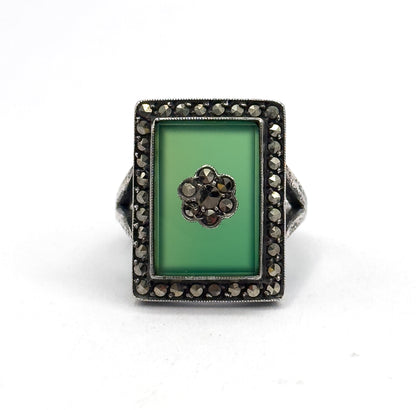 Straight down onto the flat rectangular face, the chrysoprase and its marcasite flower centred within the full square halo, the shank tucked out of sight behind the bezel.