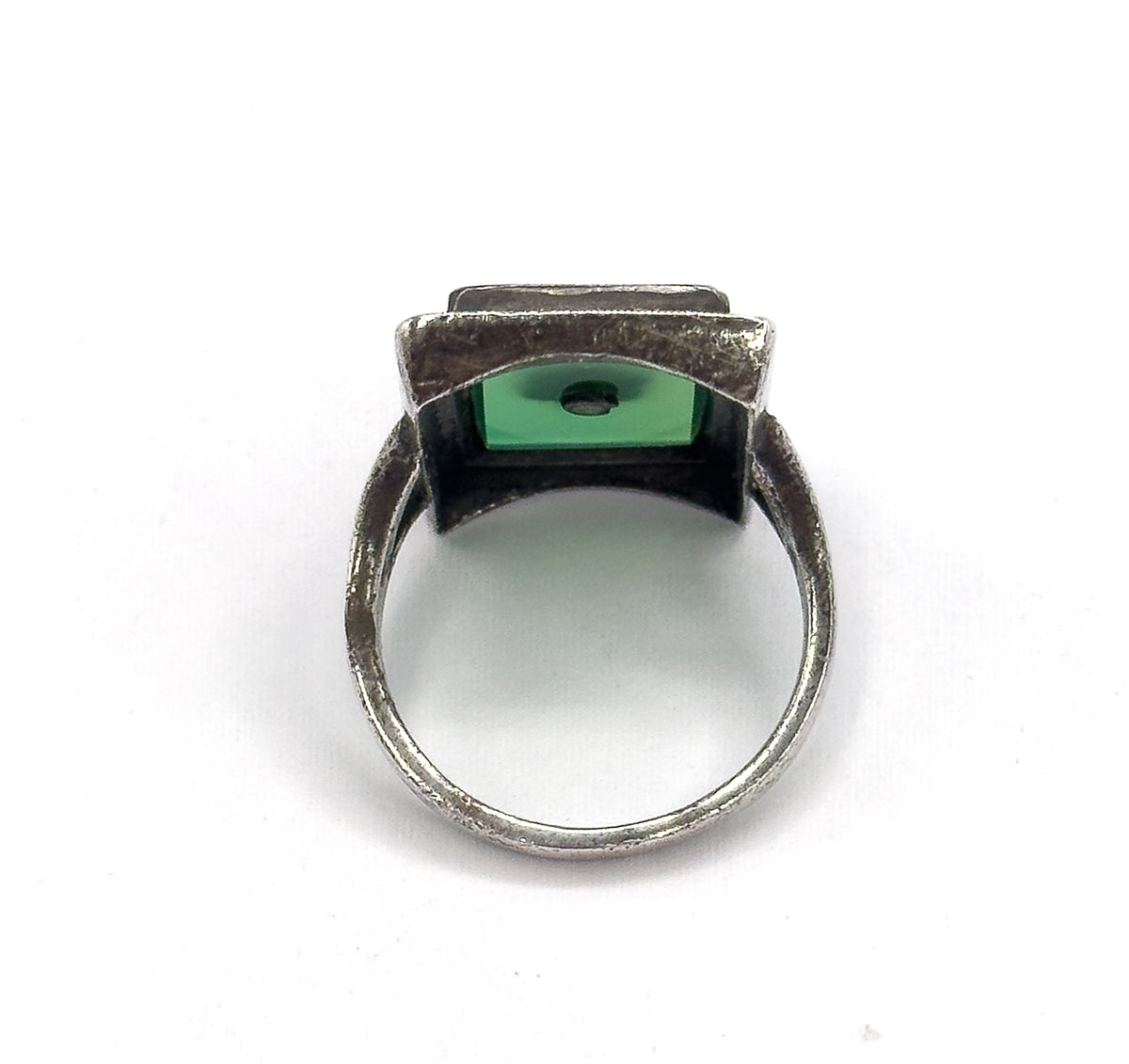 Viewed from beneath and behind, the open back of the bezel reveals the underside of the green chrysoprase with its small central drill hole, framed by the darkened silver shank.